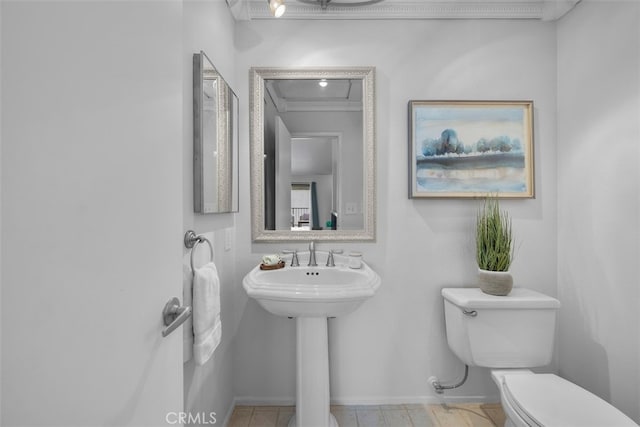half bathroom with a sink, ornamental molding, toilet, and baseboards