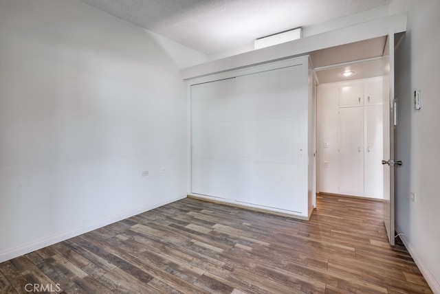 unfurnished bedroom featuring a closet, baseboards, and wood finished floors