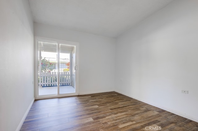 spare room with baseboards and wood finished floors