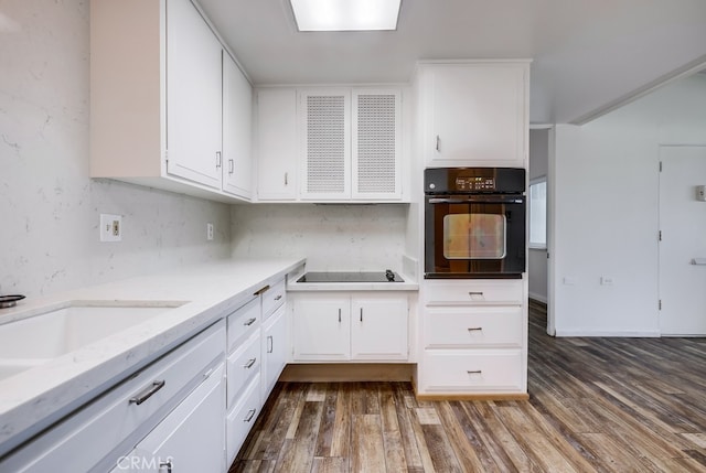kitchen featuring white cabinets, dark wood-type flooring, tasteful backsplash, and black appliances