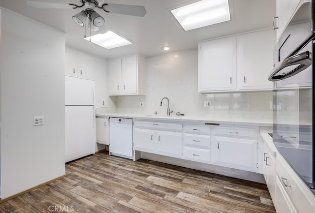 kitchen with white appliances, white cabinets, ceiling fan, and a sink