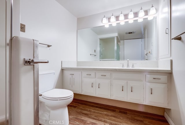 bathroom with toilet, vanity, visible vents, and wood finished floors
