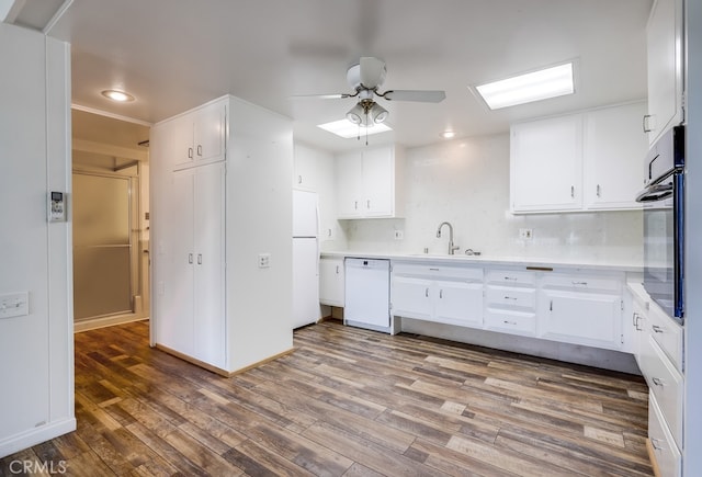 kitchen featuring wood finished floors, a ceiling fan, white cabinets, white appliances, and light countertops