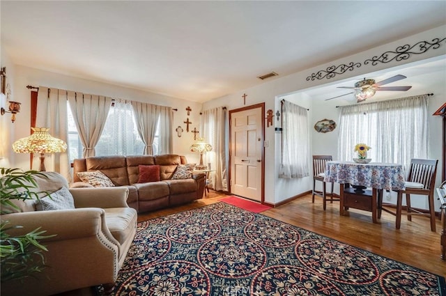living room with ceiling fan, visible vents, and wood finished floors