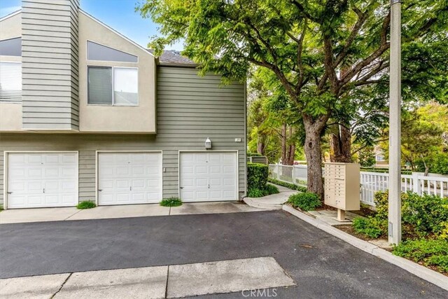 garage featuring asphalt driveway and fence