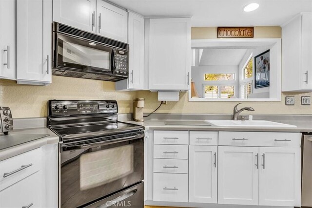 kitchen featuring black appliances, a sink, and white cabinets