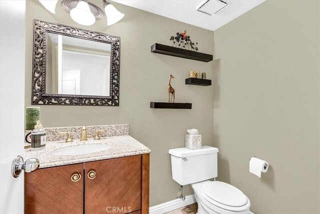 half bath featuring toilet, vanity, and baseboards