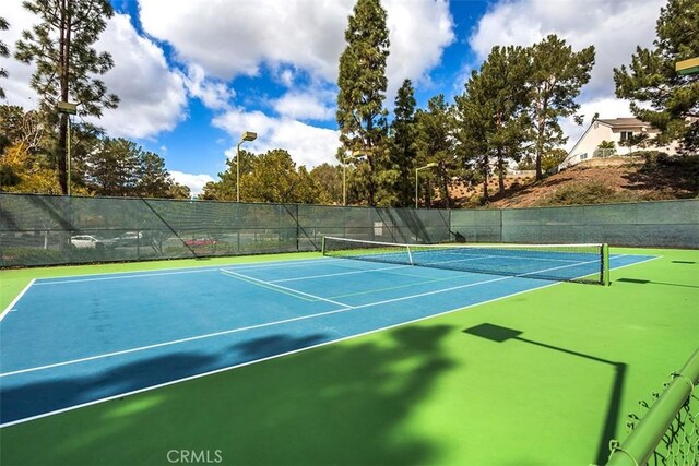 view of tennis court featuring community basketball court and fence