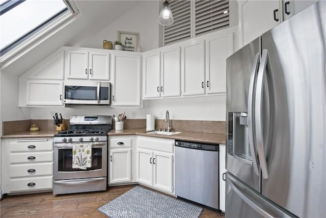 kitchen featuring appliances with stainless steel finishes, a sink, white cabinetry, and dark wood-style floors