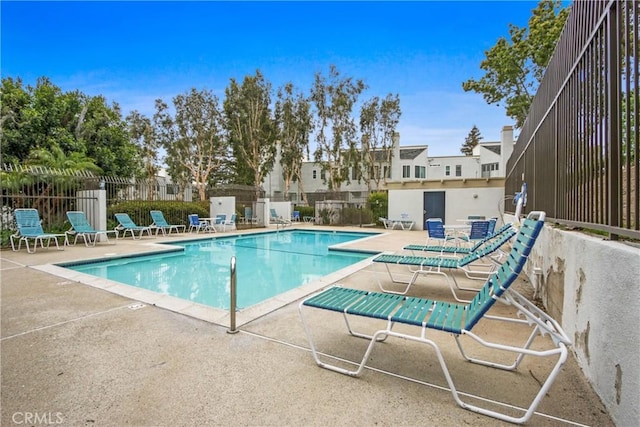 community pool with a patio area and fence