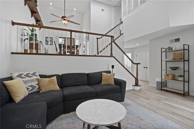 living area featuring ceiling fan, stairway, wood finished floors, a high ceiling, and recessed lighting