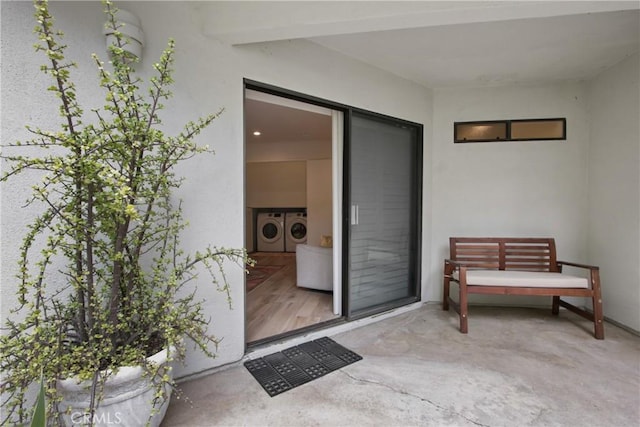 property entrance featuring washing machine and clothes dryer and stucco siding
