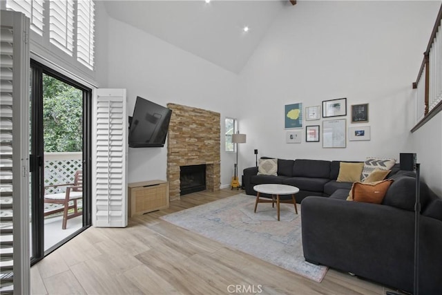living room featuring high vaulted ceiling, a fireplace, and beam ceiling