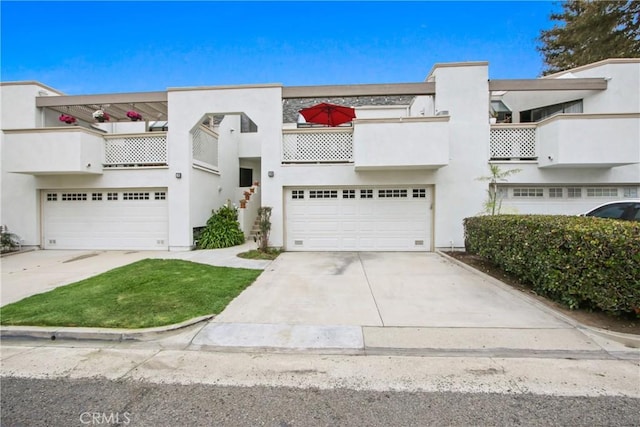 art deco home with a balcony, an attached garage, concrete driveway, and stucco siding