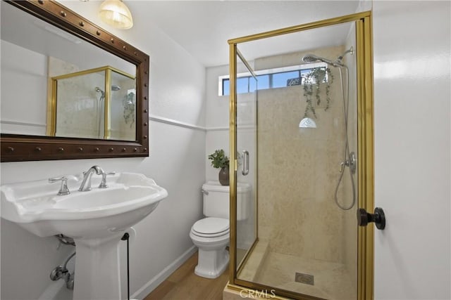 bathroom featuring a stall shower, toilet, wood finished floors, and baseboards