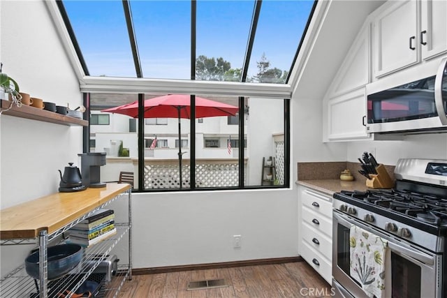 kitchen featuring stainless steel appliances, dark wood-style flooring, white cabinetry, and baseboards