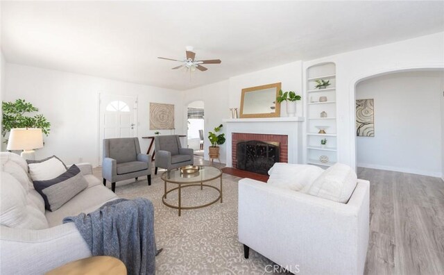 1949 Lancewood Ave, Hacienda Heights, CA 91745 - living area featuring arched walkways, wood finished floors, ceiling fan, a brick fireplace, and baseboards