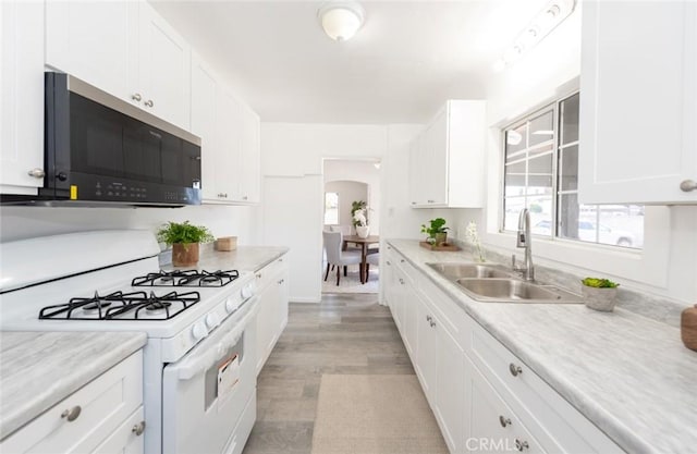 1949 Lancewood Ave, Hacienda Heights, CA 91745 - kitchen featuring white range with gas cooktop, stainless steel microwave, a sink, arched walkways, and white cabinets