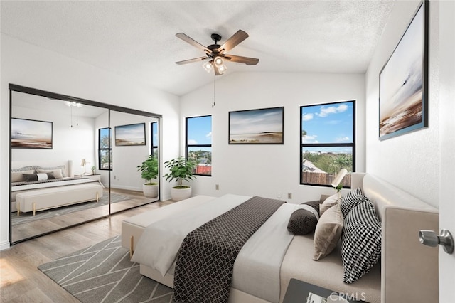 bedroom featuring lofted ceiling, ceiling fan, a textured ceiling, and wood finished floors