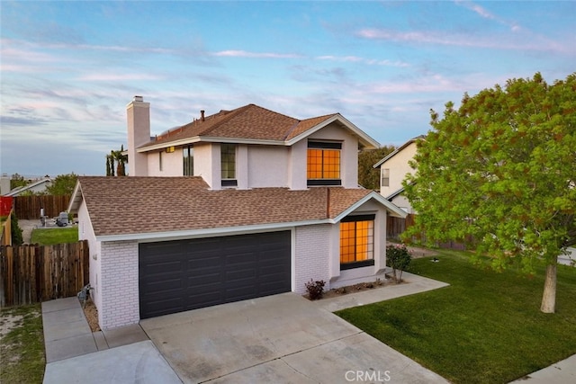 traditional-style home featuring an attached garage, fence, a front lawn, brick siding, and driveway