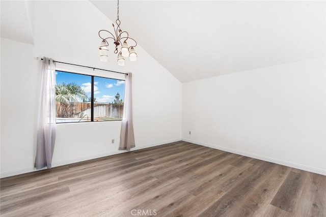 additional living space with vaulted ceiling, an inviting chandelier, baseboards, and wood finished floors