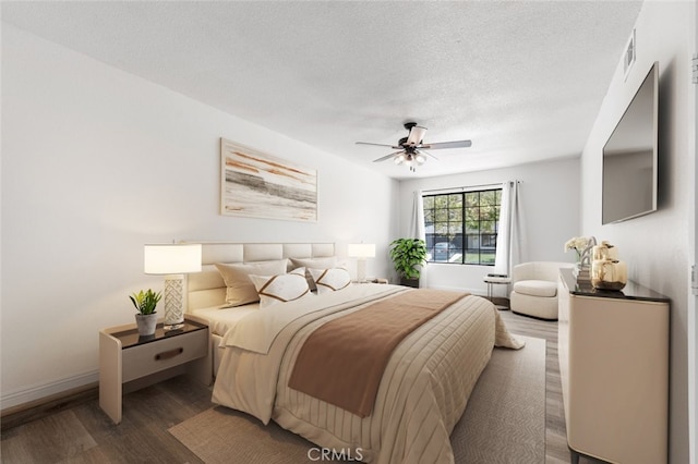 bedroom with ceiling fan, visible vents, a textured ceiling, and wood finished floors
