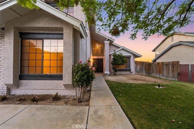 exterior space featuring stucco siding, fence, and a lawn