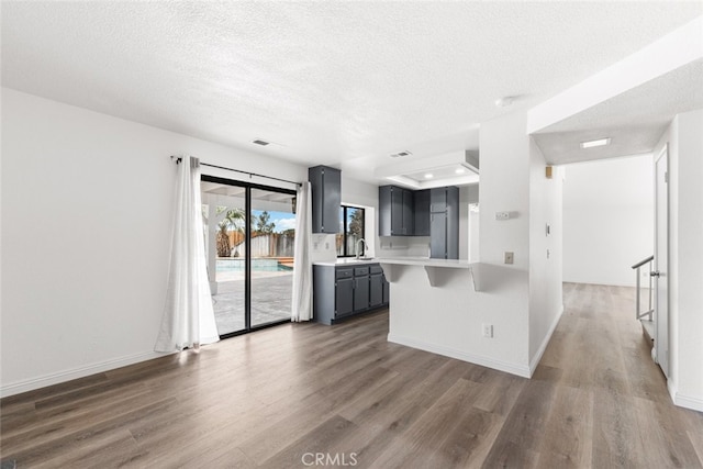 kitchen with a sink, a textured ceiling, light countertops, and wood finished floors