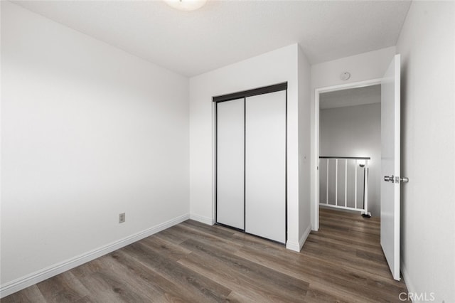 unfurnished bedroom with baseboards, a closet, and wood finished floors