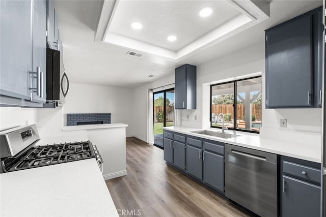 kitchen with dark wood finished floors, visible vents, a sink, light countertops, and appliances with stainless steel finishes