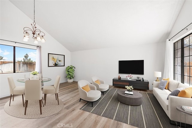 living area featuring baseboards, a notable chandelier, wood finished floors, and vaulted ceiling