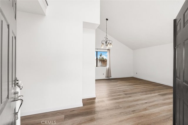 additional living space with lofted ceiling, baseboards, a chandelier, and wood finished floors