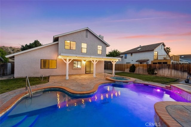 back of house with a patio area, stucco siding, a pool with connected hot tub, and a fenced backyard