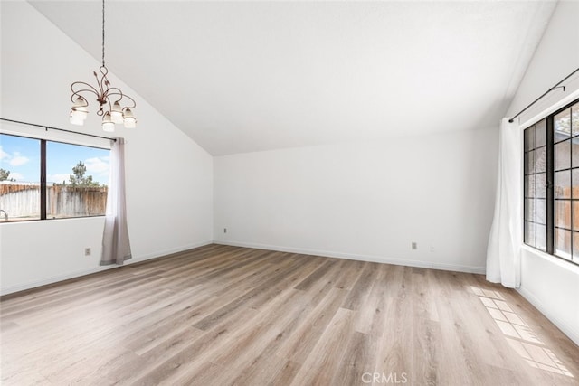 additional living space featuring baseboards, a notable chandelier, light wood-style flooring, and vaulted ceiling