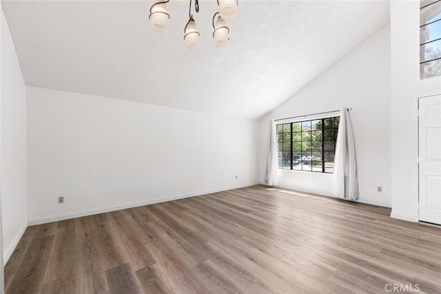 unfurnished living room featuring a chandelier, baseboards, high vaulted ceiling, and wood finished floors