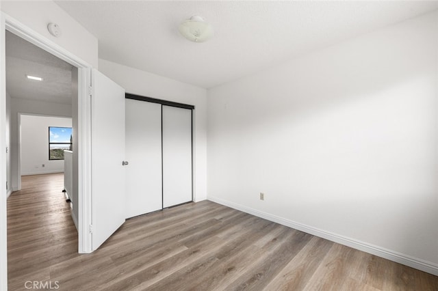 unfurnished bedroom with baseboards, a closet, and wood finished floors