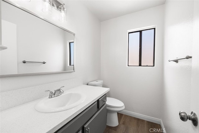 bathroom with vanity, toilet, baseboards, and wood finished floors