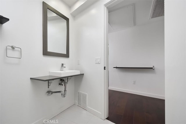 bathroom with baseboards, visible vents, and a sink