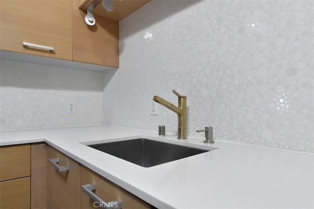 kitchen featuring a sink, brown cabinetry, tasteful backsplash, light countertops, and modern cabinets