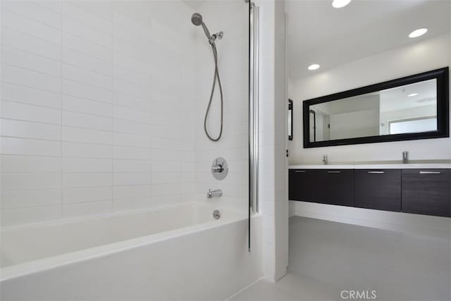 full bathroom with recessed lighting, double vanity, a sink, and washtub / shower combination