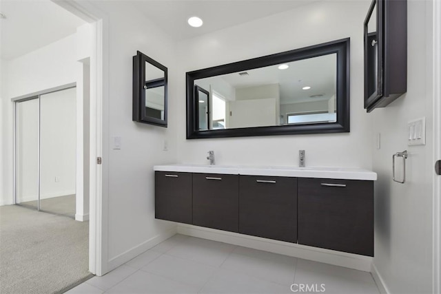 bathroom featuring a sink, double vanity, baseboards, and tile patterned flooring