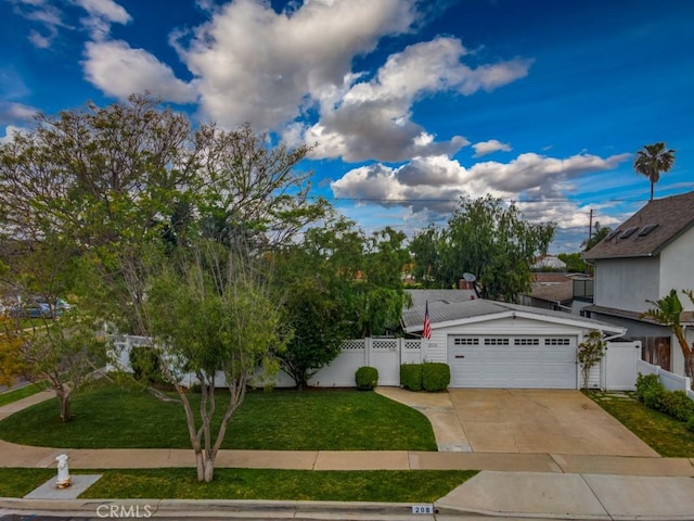 view of front of property featuring concrete driveway, a garage, fence, and a front yard