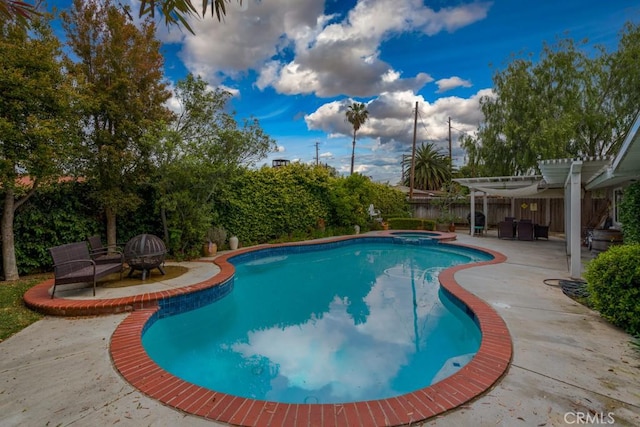 view of swimming pool featuring a pool with connected hot tub, a patio area, a fenced backyard, a pergola, and an outdoor fire pit