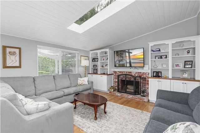 living area featuring a fireplace, light wood finished floors, lofted ceiling with skylight, and wood ceiling