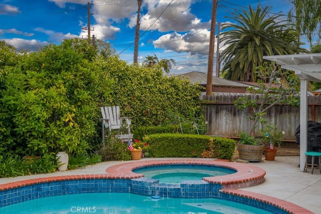 view of swimming pool with a patio area, a pool with connected hot tub, and fence