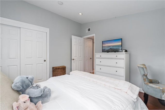 bedroom with a closet, visible vents, and wood finished floors
