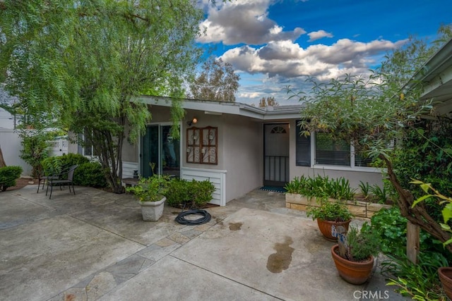 property entrance with a patio and stucco siding
