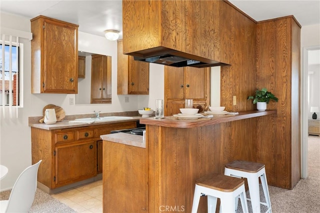 660 Stanley Ave, Long Beach, CA 90814 - kitchen featuring a sink, extractor fan, a peninsula, brown cabinets, and a breakfast bar