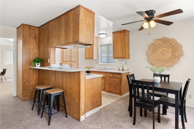 660 Stanley Ave, Long Beach, CA 90814 - kitchen featuring a ceiling fan, brown cabinets, light countertops, and light colored carpet
