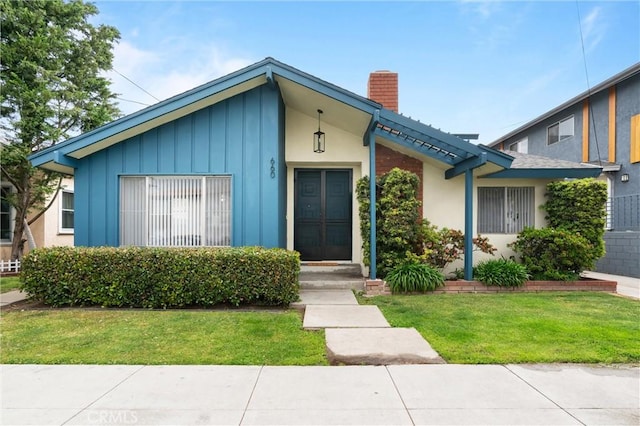660 Stanley Ave, Long Beach, CA 90814 - view of front of house with a chimney, board and batten siding, and a front lawn